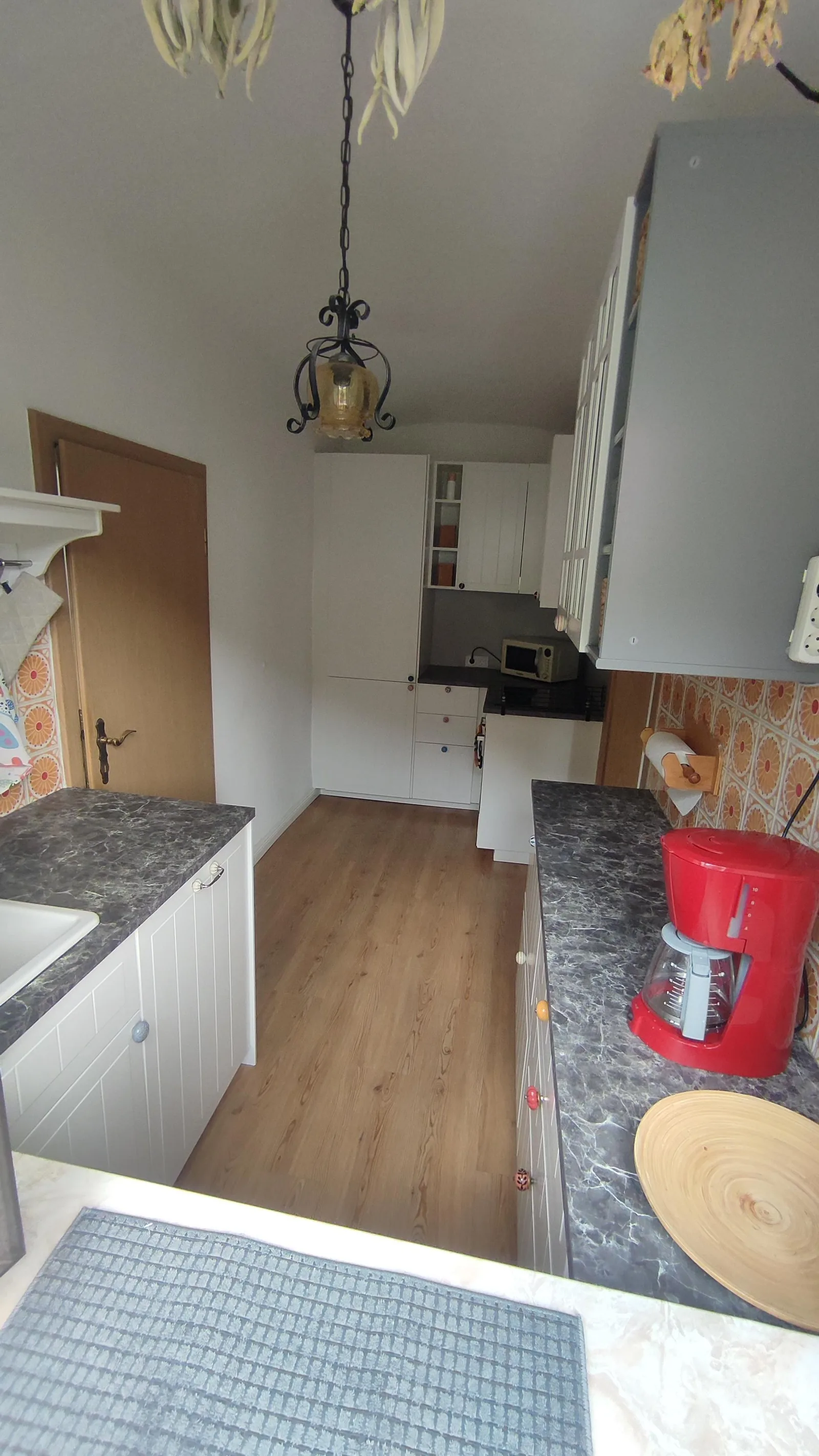 Küche der Ferienwohnung mit weißen Schränken, dunkler Arbeitsplatte und Kaffeemaschine